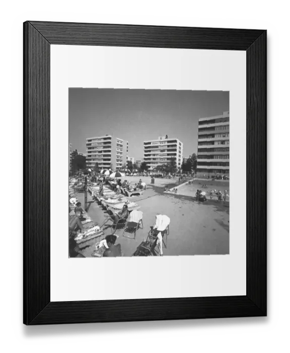 Framed Print : People relaxing at swimming pool surrounded by apartment buildings, (B&W)