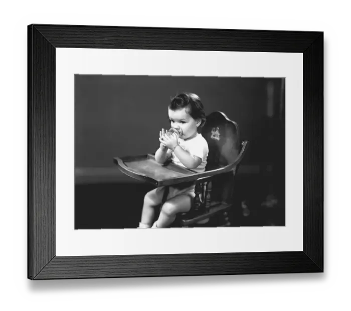Framed Print : Girl (2-3) sitting in high chair, drinking from glass, (B&W) Framed Print : Girl (2-3) sitting in high chair, drinking from glass, (B&W)