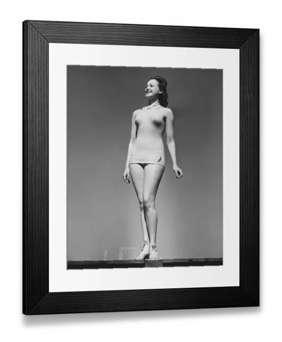 Framed Print : Woman in swimsuit posing in studio (B&W), low angle view Framed Print : Woman in swimsuit posing in studio (B&W), low angle view