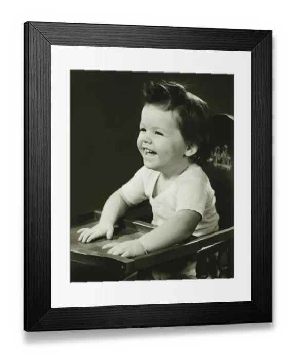 Framed Print : Smiling girl (2-3) sitting in high chair, (B&W) Framed Print : Smiling girl (2-3) sitting in high chair, (B&W)