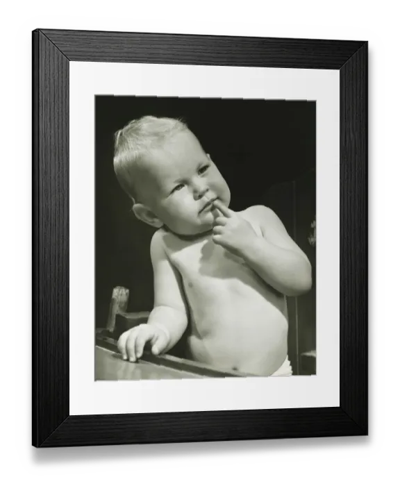 Framed Print : Baby boy (6-12 months) with finger on lips sitting in high chair, (B&W), portrait Framed Print : Baby boy (6-12 months) with finger on lips sitting in high chair, (B&W), portrait