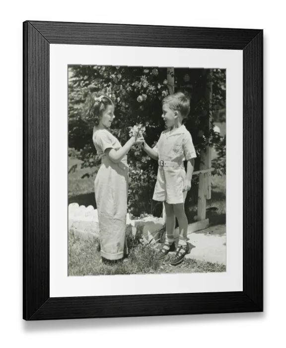 Framed Print : Boy (4-5) giving girl (4-5) flowers, (B&W)