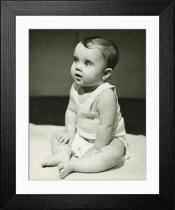 Framed Print : Baby boy (12-18 months) sitting on bedspread, (B&W), close-up Framed Print : Baby boy (12-18 months) sitting on bedspread, (B&W), close-up