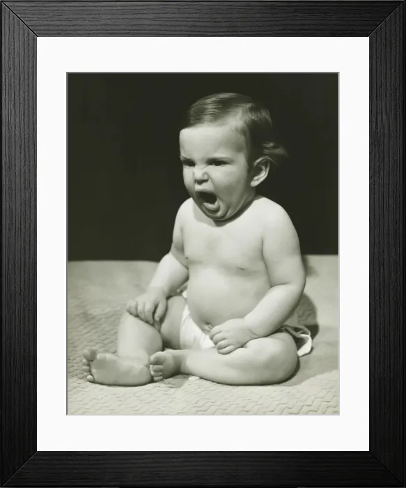 Framed Print : Baby boy (12-18 months) sitting on bedspread, yawning, (B&W) Framed Print : Baby boy (12-18 months) sitting on bedspread, yawning, (B&W)