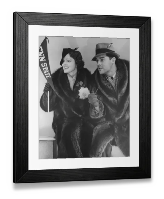 Framed Print : Young couple in fur coats sitting, facing same direction, (B&W) Framed Print : Young couple in fur coats sitting, facing same direction, (B&W)