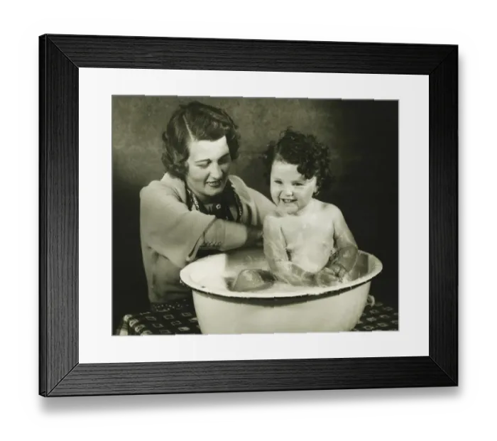 Framed Print : Mother bathing daughter (12-18 months) in basin, (B&W) Framed Print : Mother bathing daughter (12-18 months) in basin, (B&W)