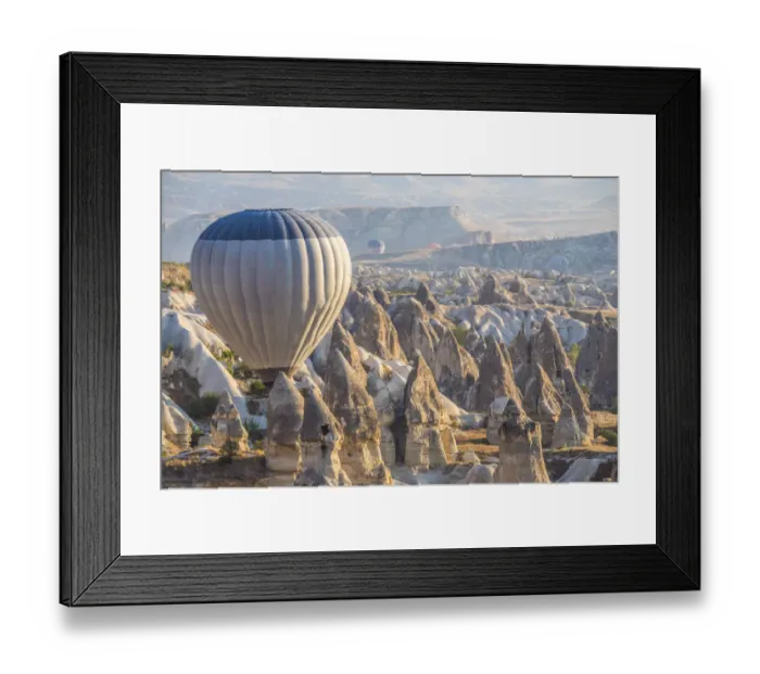 Framed Print : Hot air balloon flying over rock landscape at Cappadocia Turkey