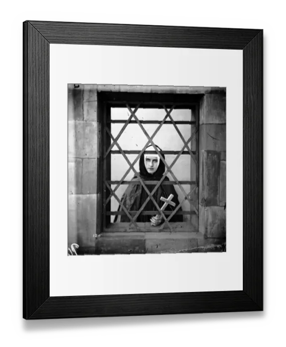 Framed Print : Young Nun. circa 1865: A young nun holding a cross whilst looking through a barred window Framed Print : Young Nun. circa 1865: A young nun holding a cross whilst looking through a barred window
