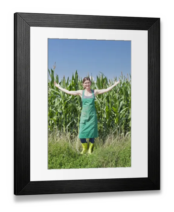 Framed Print : Young woman in work clothes standing with outstretched arms in front of a maize field, Baden-Wurttemberg, Germany Framed Print : Young woman in work clothes standing with outstretched arms in front of a maize field, Baden-Wurttemberg, Germany