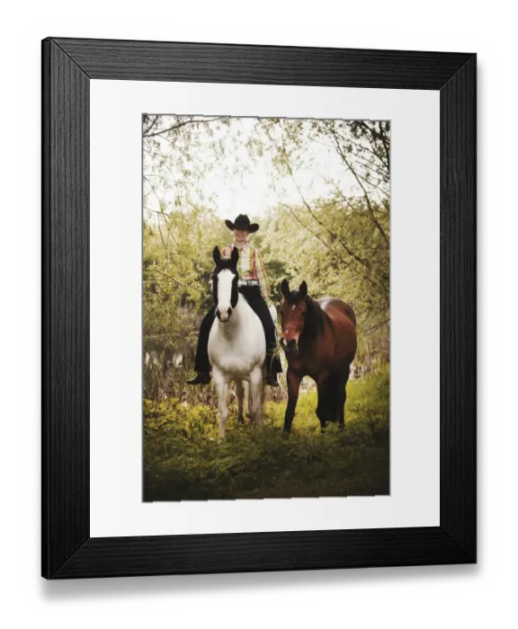 Framed Print : Female western rider on a Paint Horse, Black Tobiano colour pattern, leading a bay Shagya Arabian horse, riding bareback through the forest, Munsterland, North Rhine-Westphalia, Germany