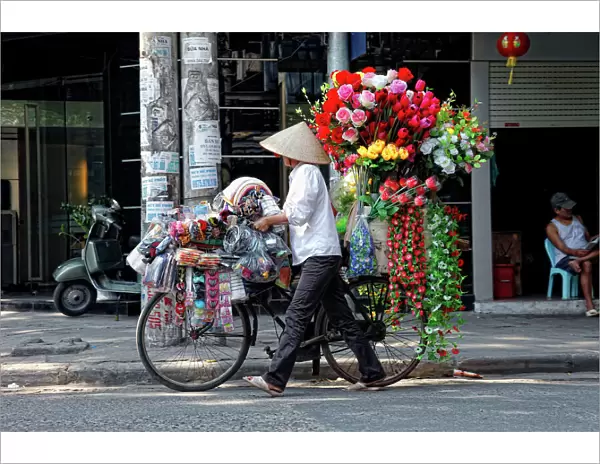 A street vendor with a bicycle selling her flowers in Hanoi, Vietnam, Asia