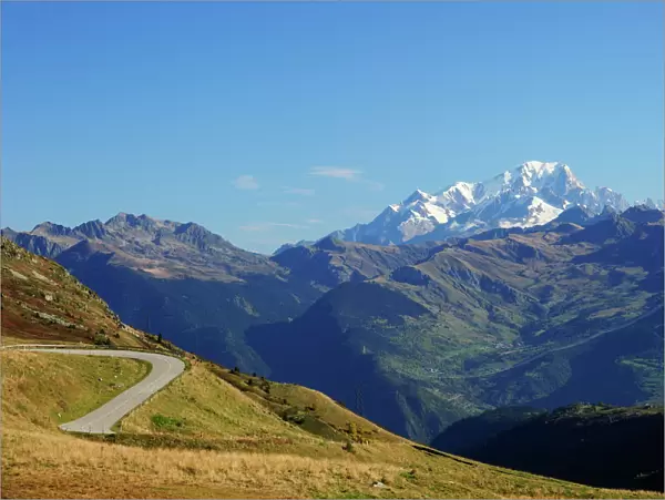 The pass road leading up to Col de la Madeleine, the snow-capped peaks of the Mont Blanc Massif at the back, Alps, France