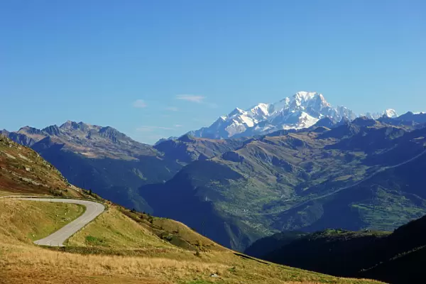 The pass road leading up to Col de la Madeleine, the snow-capped peaks of the Mont Blanc Massif at the back, Alps, France