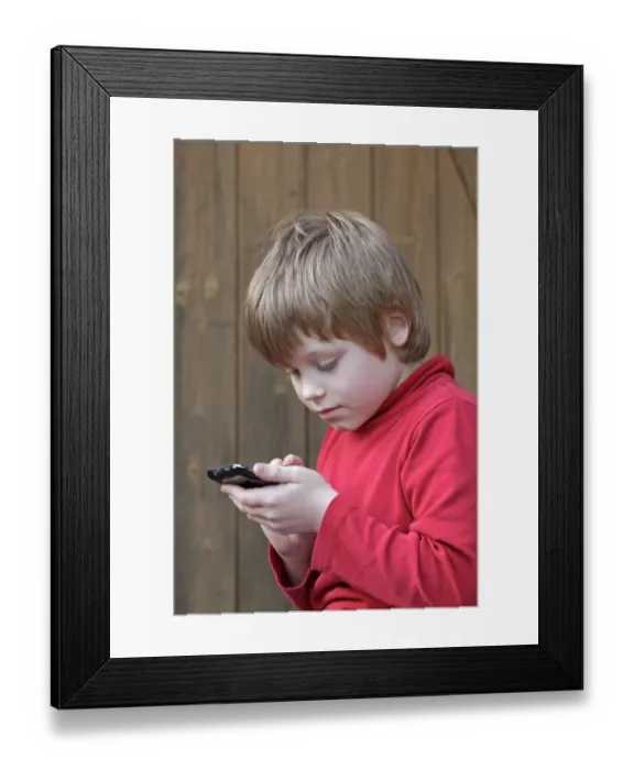 Framed Print : Boy writing a text message Framed Print : Boy writing a text message