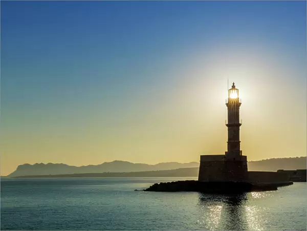 Chania lighthouse with the sun right behind, at sunrise, harbour, Chania, Crete, Greece