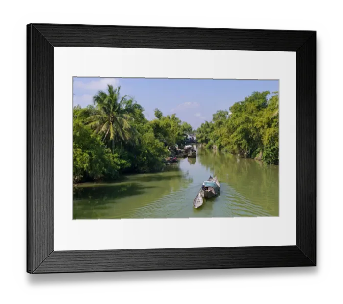 Framed Print : Small wooden motorboat passing through a water channel surrounded by tropical vegetation, Hue, Vietnam, Asia