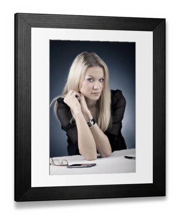 Framed Print : Young woman sitting at a desk, with moblie phone and glasses, Germany Framed Print : Young woman sitting at a desk, with moblie phone and glasses, Germany
