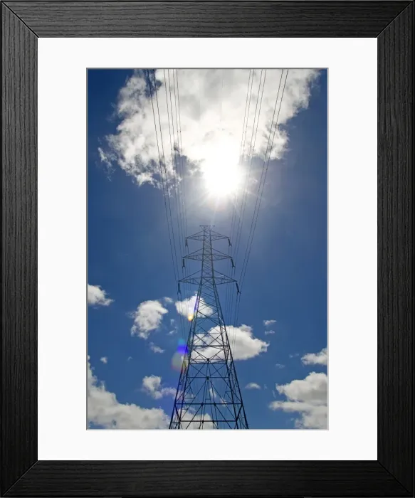Framed Print : Electricity pylon against a blue sky with clouds