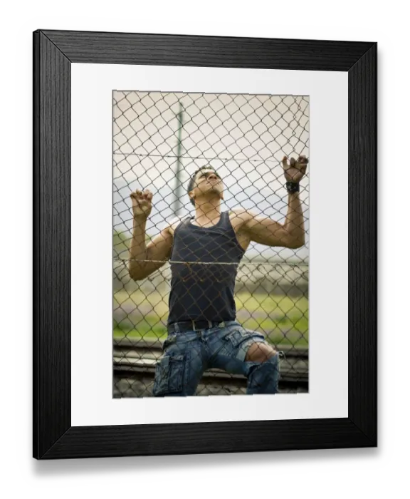 Framed Print : Young man climbing a fence