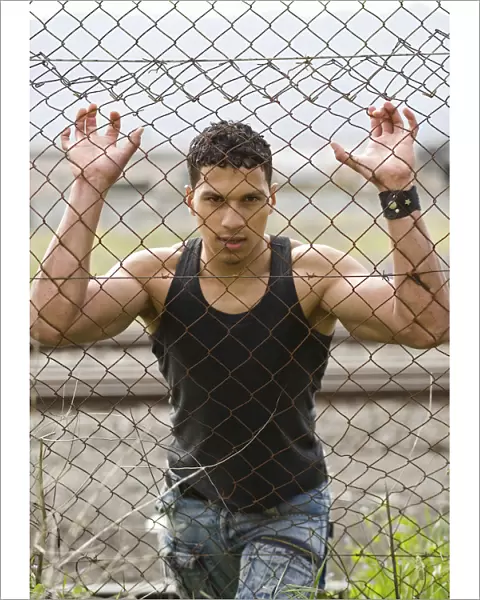 Young man holding onto a fence