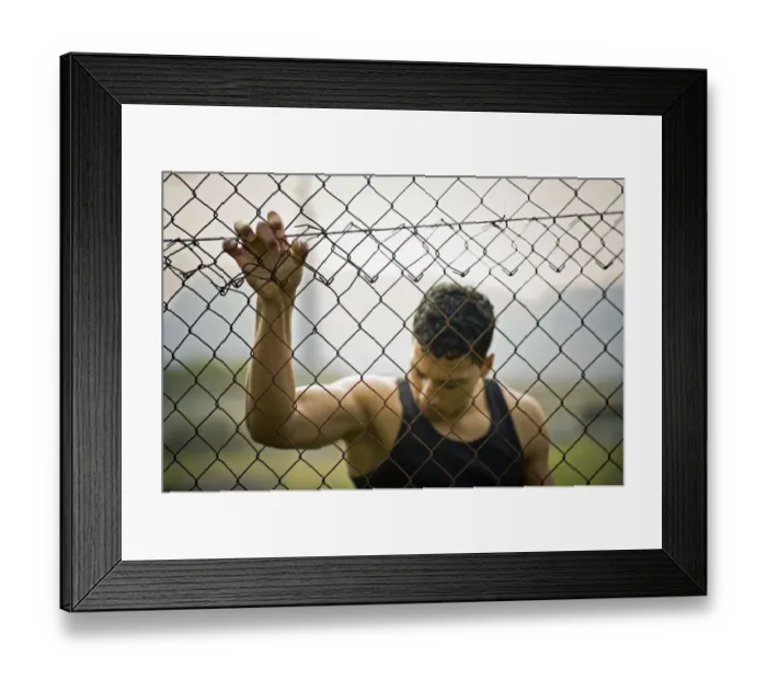 Framed Print : Young man holding onto a fence Framed Print : Young man holding onto a fence