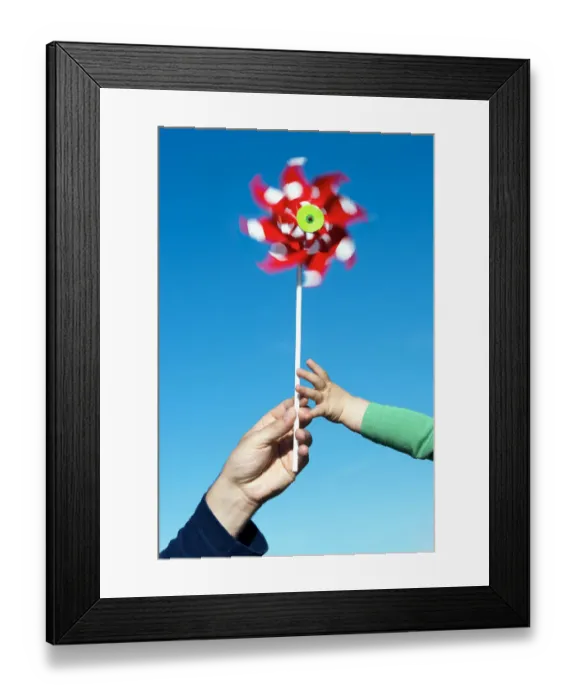 Framed Print : Man passing a wind wheel to a child, symbolic image for environmental education, alternative energy and sustainability Framed Print : Man passing a wind wheel to a child, symbolic image for environmental education, alternative energy and sustainability