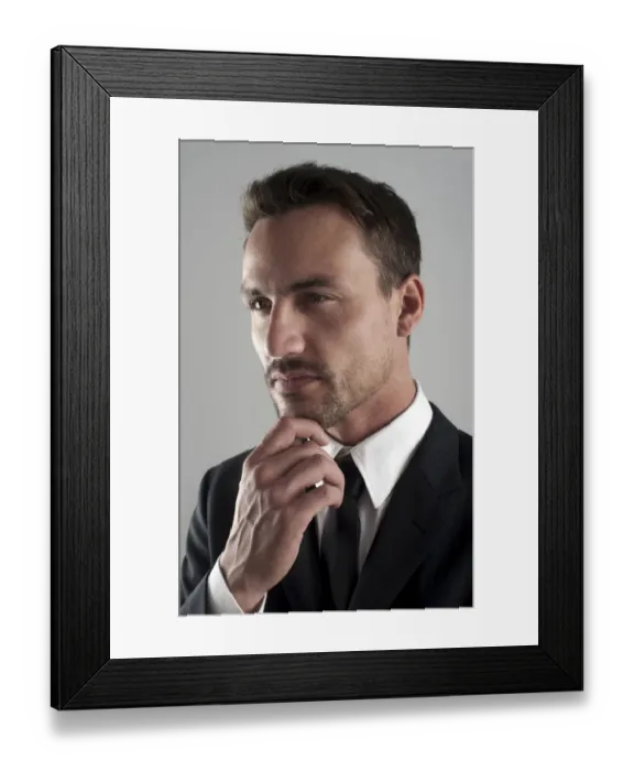 Framed Print : Young businessman wearing a suit with his hand on his chin, pensive, portrait Framed Print : Young businessman wearing a suit with his hand on his chin, pensive, portrait