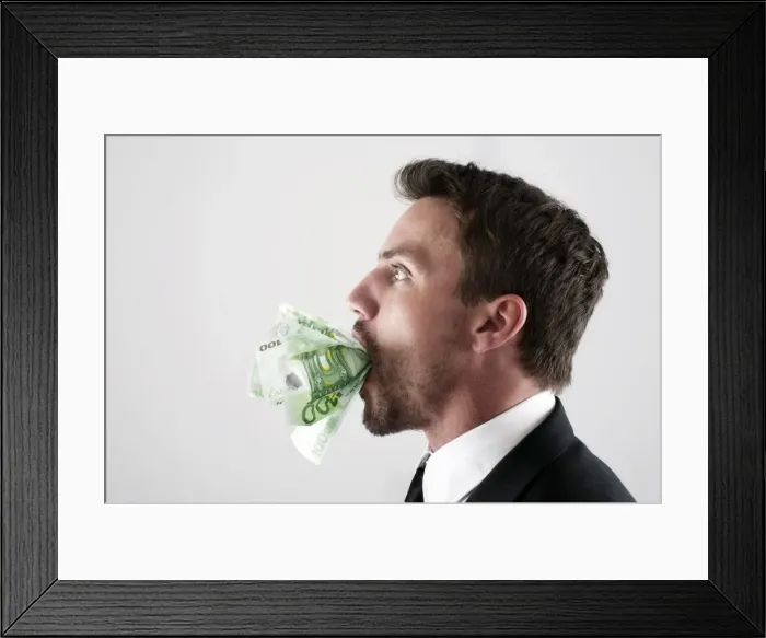 Framed Print : Young man wearing a suit with 100-euro notes stuffed into his mouth Framed Print : Young man wearing a suit with 100-euro notes stuffed into his mouth