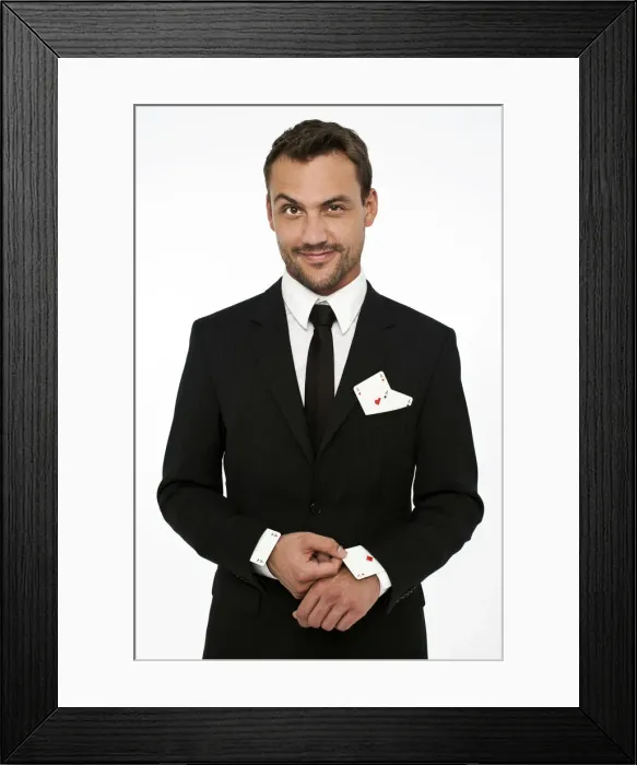 Framed Print : Man wearing a suit pulling an ace of diamonds out of his sleeve with other aces in his pocket
