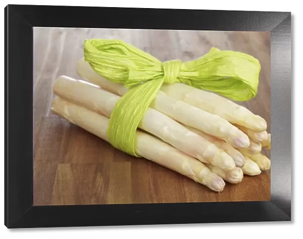 Fresh unpeeled white asparagus, wrapped with a green ribbon
