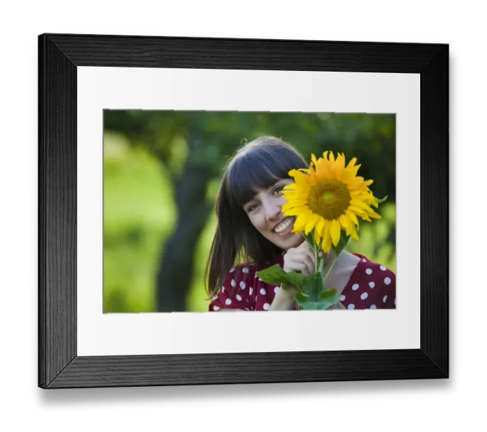 Framed Print : Young woman, 25, holding a sunflower in front of her face Framed Print : Young woman, 25, holding a sunflower in front of her face