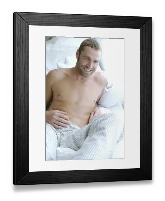 Framed Print : Bare-chested man lying on bed in bedroom suffused with light Framed Print : Bare-chested man lying on bed in bedroom suffused with light