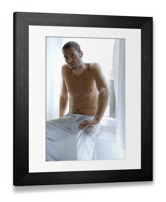 Framed Print : Bare-chested man sitting in bedroom suffused with light