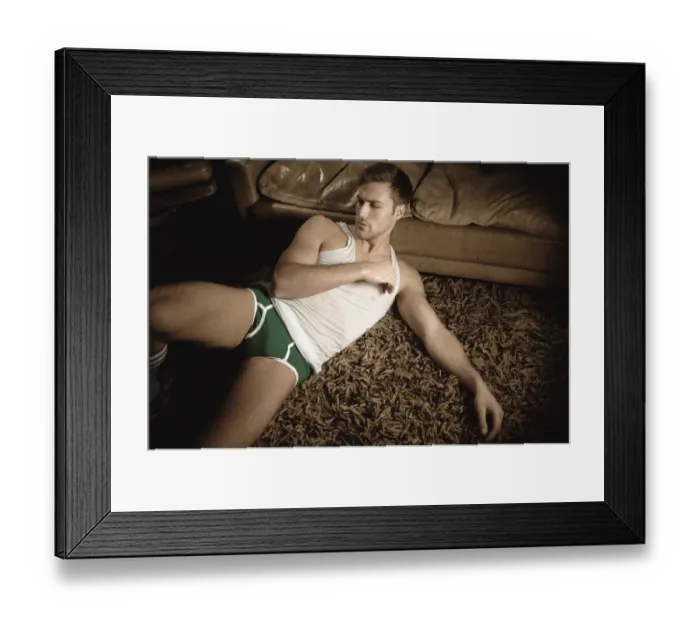 Framed Print : Man in underwear lying on the floor in front of a leather sofa Framed Print : Man in underwear lying on the floor in front of a leather sofa