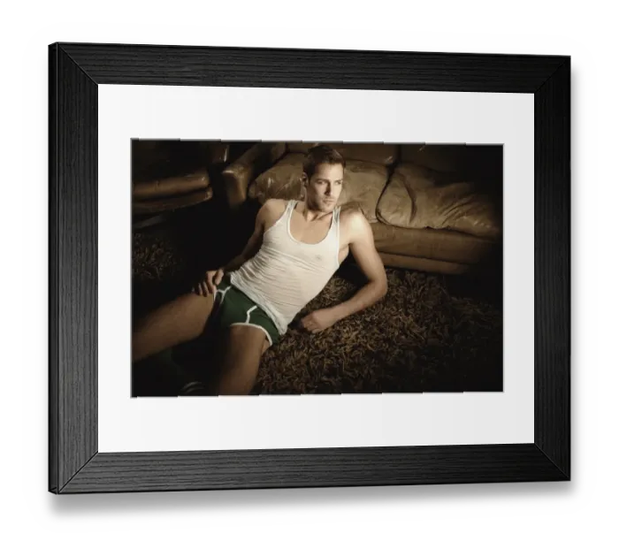 Framed Print : Man in underwear lying on the floor in front of a leather sofa