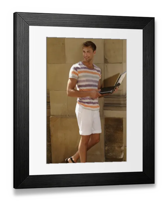 Framed Print : Young man with laptop standing in front of a wall