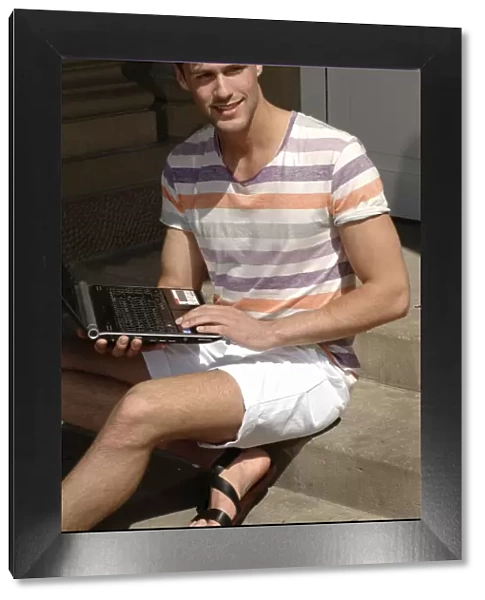 Young man with laptop sitting on steps