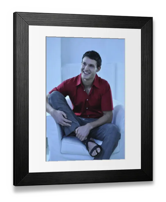 Framed Print : Young man wearing a red shirt sitting in an armchair, smiling Framed Print : Young man wearing a red shirt sitting in an armchair, smiling