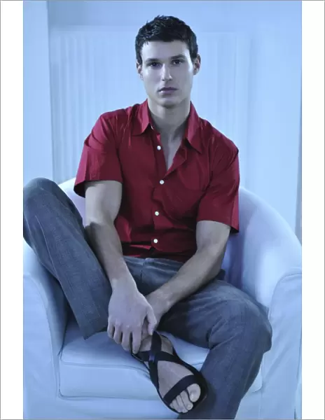 Young man wearing a red shirt sitting in an armchair