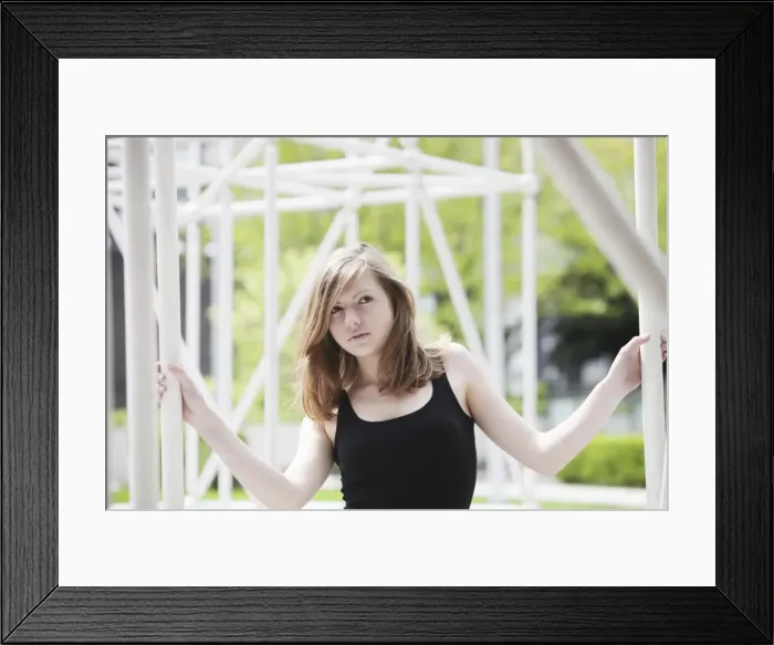 Framed Print : Young woman holding onto a metal construction Framed Print : Young woman holding onto a metal construction