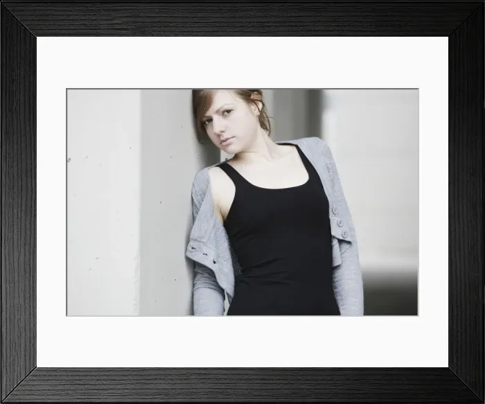 Framed Print : Young woman leaning against a wall
