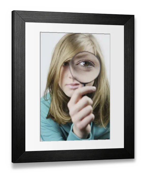 Framed Print : Young woman with magnifying glass in front of her eye Framed Print : Young woman with magnifying glass in front of her eye