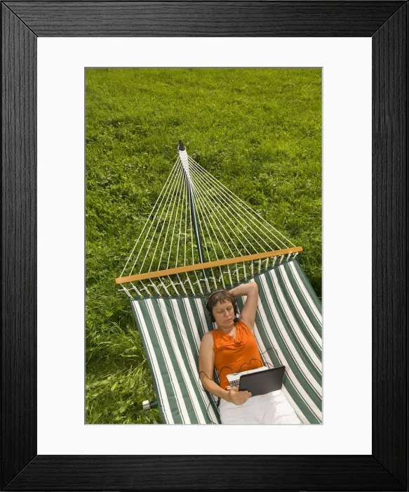 Framed Print : Senior woman with netbook and headset lying in a hammock Framed Print : Senior woman with netbook and headset lying in a hammock