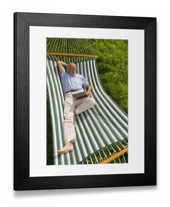 Framed Print : Elderly gentleman lying in a hammock with a netbook Framed Print : Elderly gentleman lying in a hammock with a netbook