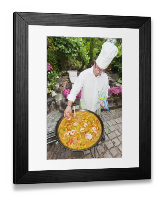 Framed Print : Cook preparing a paella, a Spanish rice dish, adding prawns, series, no. 3