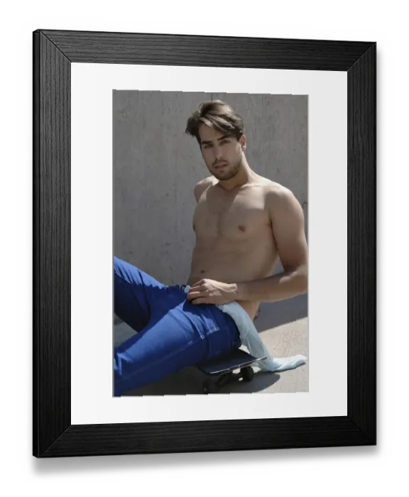Framed Print : Young shirtless skater in front of a concrete wall, sitting on his skateboard