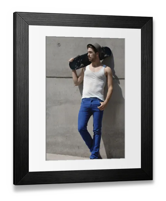 Framed Print : Young skateboarder standing in front of a concrete wall Framed Print : Young skateboarder standing in front of a concrete wall