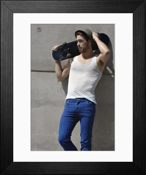 Framed Print : Young skateboarder standing in front of a concrete wall Framed Print : Young skateboarder standing in front of a concrete wall