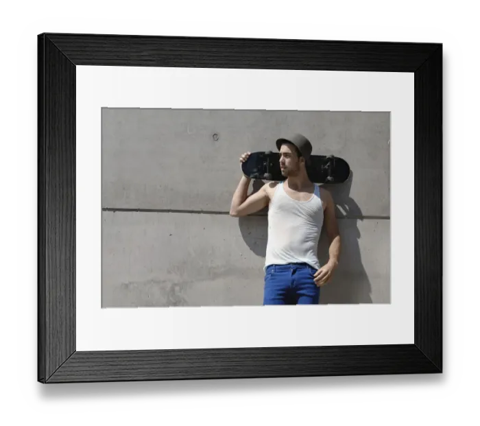 Framed Print : Young skateboarder standing in front of a concrete wall Framed Print : Young skateboarder standing in front of a concrete wall