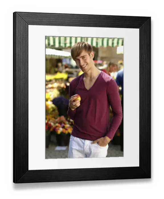 Framed Print : Young happy man holding an apple at a market Framed Print : Young happy man holding an apple at a market